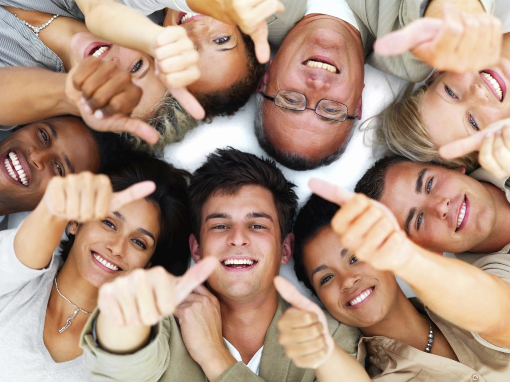 Skilled team of professionals meet objectives Group of diverse people smiling and giving thumbs up while lying on the floor.
